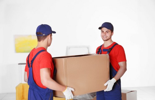 Removal professionals handling desks and equipment in a busy London setting
